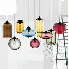 a bunch of different colored glass lights hanging from a light fixture with ladder in the background