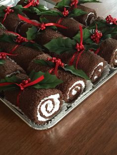 chocolate roll decorated with holly leaves and red berries on a platter for christmas desserts