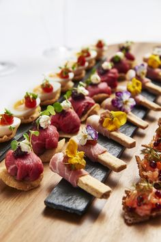 a wooden board topped with lots of different types of appetizers on top of it