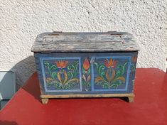 an old painted chest on a red table