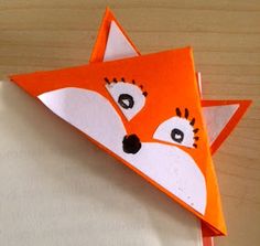 an origami fox head on top of a piece of paper