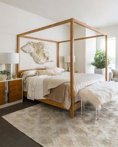 a bedroom with a four poster bed, white walls and rugs on the floor