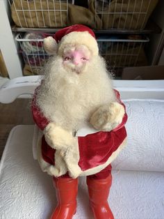 a santa clause doll sitting on top of a white towel and red rubber booties