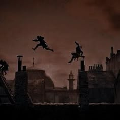 the silhouettes of two people jumping over rooftops in front of a dark sky