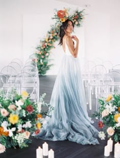 a woman is standing in front of chairs with flowers on the head and candles around her