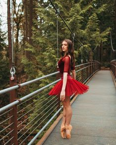 a woman in a red dress is standing on a bridge