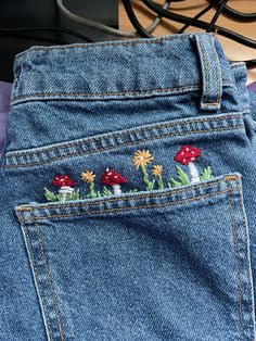 a pair of jeans with embroidered mushrooms on them