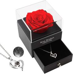 a red rose in a clear box with two matching necklaces