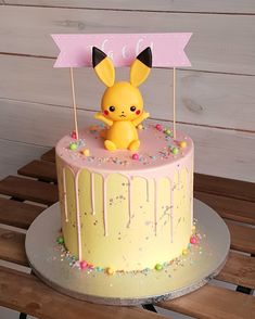 a pokemon cake is decorated with sprinkles and a pikachu figurine