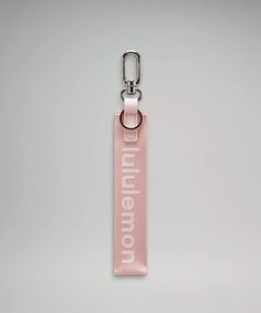 a pink keychain with the words millennium on it, hanging from a metal hook