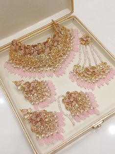 a box with some pink and gold jewelry in it