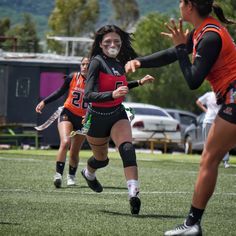 the girls are playing frisbee on the field in their sport uniforms and face masks