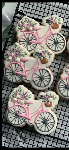 decorated cookies in the shape of bicycles are on a cooling rack with flowers and leaves