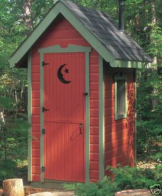 a small red outhouse in the woods