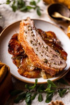 two pieces of meat on a plate with bananas and other food items around the table