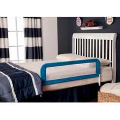 a child's bed with a blue and white rail next to it in a bedroom