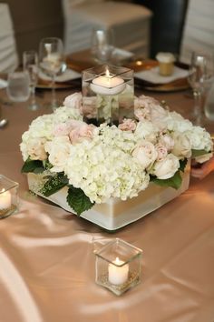 a centerpiece with flowers and candles on a table