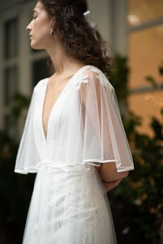 a woman in a white wedding dress with a veil on her head, looking off to the side