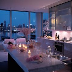 a kitchen with candles on the counter next to an oven and sink in front of large windows