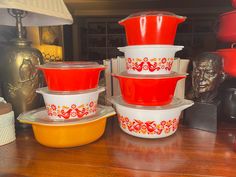 red and white dishes are stacked on top of each other in front of a lamp