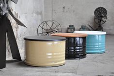 three different colored stools sitting next to each other in a room with an old wall