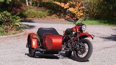 a red motorcycle parked on top of a gravel road