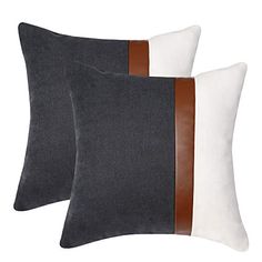 two black and white pillows with brown leather trims on them, one in grey and the other in white