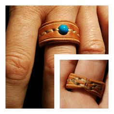 a person's hand holding a ring with a turquoise stone in the middle and brown leather band