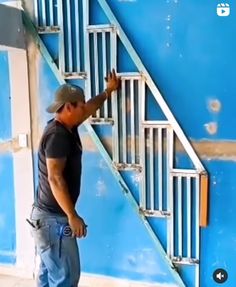 a man standing in front of a blue wall next to a white stair case and hand rail