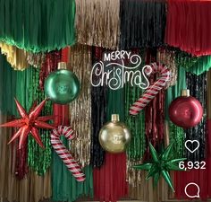 christmas decorations are hanging on the wall in front of red, green and gold curtains