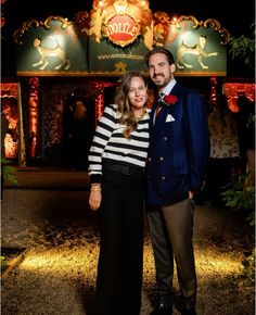 a man and woman standing next to each other in front of a circus sign at night