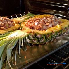 two pineapples sitting on top of an oven rack covered in meat and veggies