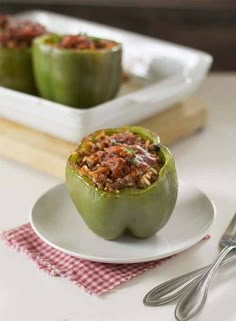 two green peppers sitting on top of a white plate