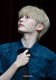 a young man wearing a blue shirt and black tie with his hands on his chest