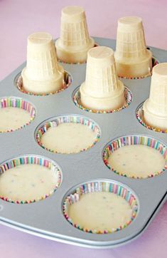 a muffin tin filled with cupcake batters on top of a pink table