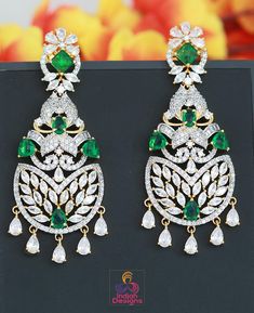 Stunning statement earrings, featuring a luxurious combination of emerald green stones and dazzling white crystals. These earrings are meticulously crafted with a gold-plated floral design that exudes elegance and sophistication. Perfect for weddings, festive occasions, or special events, these earrings add a regal touch to any outfit. The intricate detailing, paired with the vibrant green and shimmering crystals, creates a captivating piece of jewelry that is both timeless and versatile. Design Luxury Green Jhumkas With Intricate Design, Elegant Green Danglers For Celebration, Elegant Green Chandelier Earrings For Festive Occasions, Elegant Green Drop Earrings, Elegant Green Crystal Earrings For Festive Occasions, Elegant Green Bridal Earrings For Festive Occasions, Green Drop Earrings For Celebration, Green Cubic Zirconia Earrings For Celebration, Festive Green Hand Set Earrings