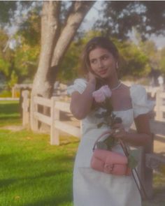 a woman in a white dress holding a pink rose