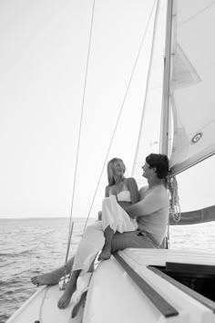 two women sitting on the back of a sailboat in the ocean, looking at each other