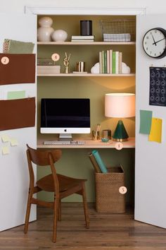 a desk with a computer on top of it next to a wall mounted clock and lamp