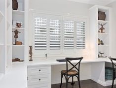 two chairs are sitting at a desk in front of white shuttered windows with deer heads on them