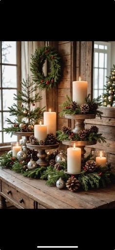 candles are arranged on a table with pine cones and greenery