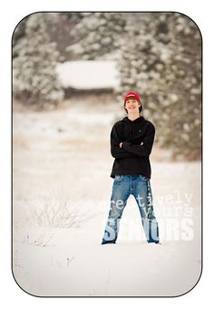 a man standing in the snow with his arms crossed and wearing a red beanie