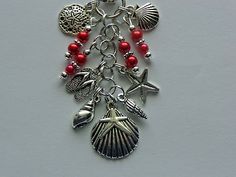 a necklace with charms on it and shells hanging from the bottom, along with red beads