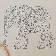 an elephant with intricate designs on it's body is next to some scissors and thread