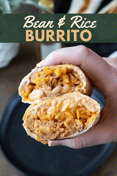 a hand holding a burrito filled with meat and cheese