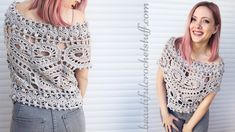 a woman with pink hair wearing a crochet top and grey jeans standing in front of a white wall