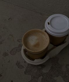 two coffee cups sitting on top of each other in front of a concrete wall and floor