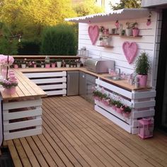 an outdoor kitchen made out of pallets and wooden boards with potted plants on top