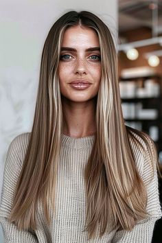 Woman with long, sleek straight hair and bold blunt ends wearing a beige sweater