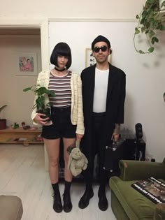 two people standing next to each other holding plants